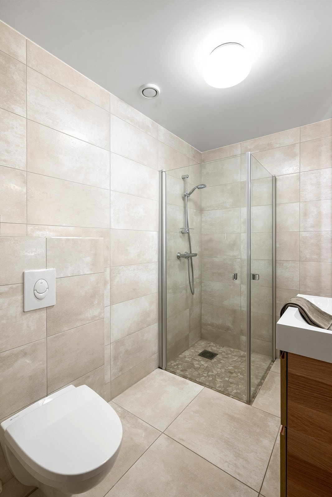 Rommet er innredet med dusjhjørne, seksjon med skuffer og servant. Vegghengt toalett. Galleribilde