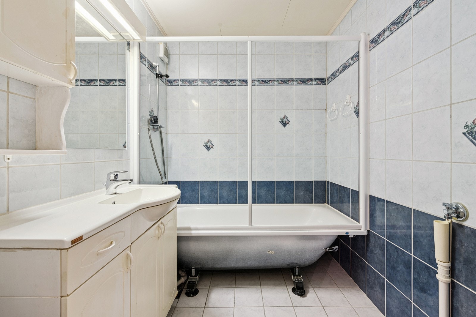 Bad med badekar. Servant med innredning og overskap med speil. Galleribilde