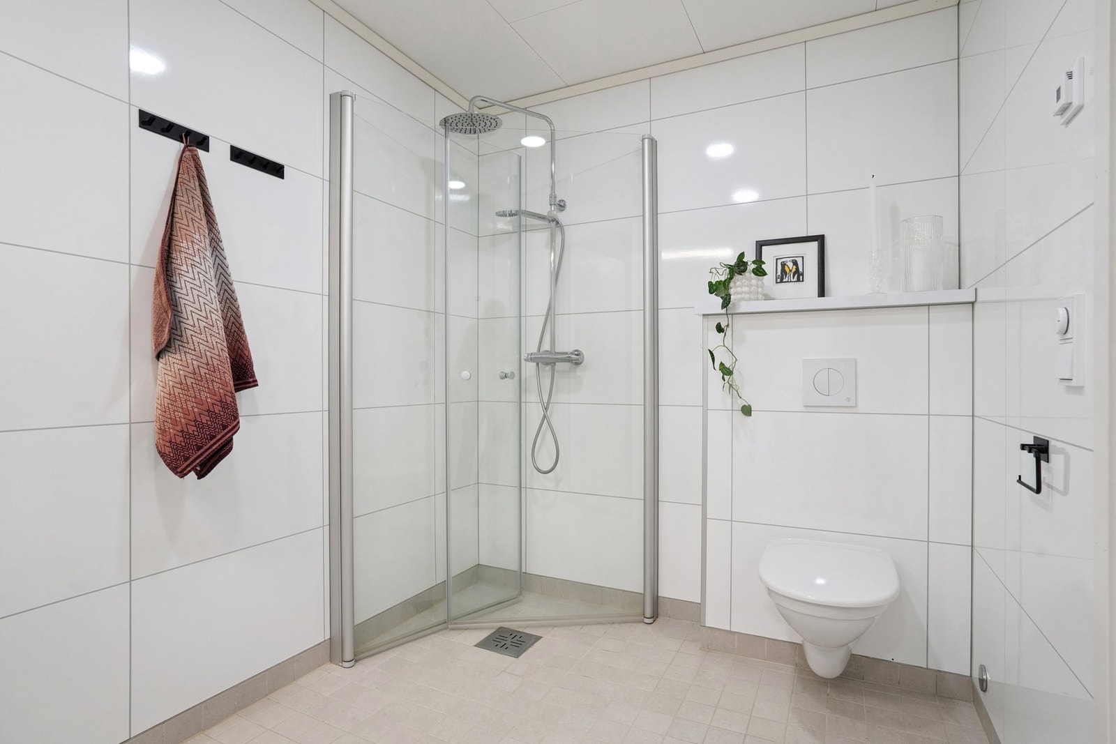 Rommet er innredet med vegghengt toalett, dusjhjørnet, servant på møbel og speilskap. Galleribilde