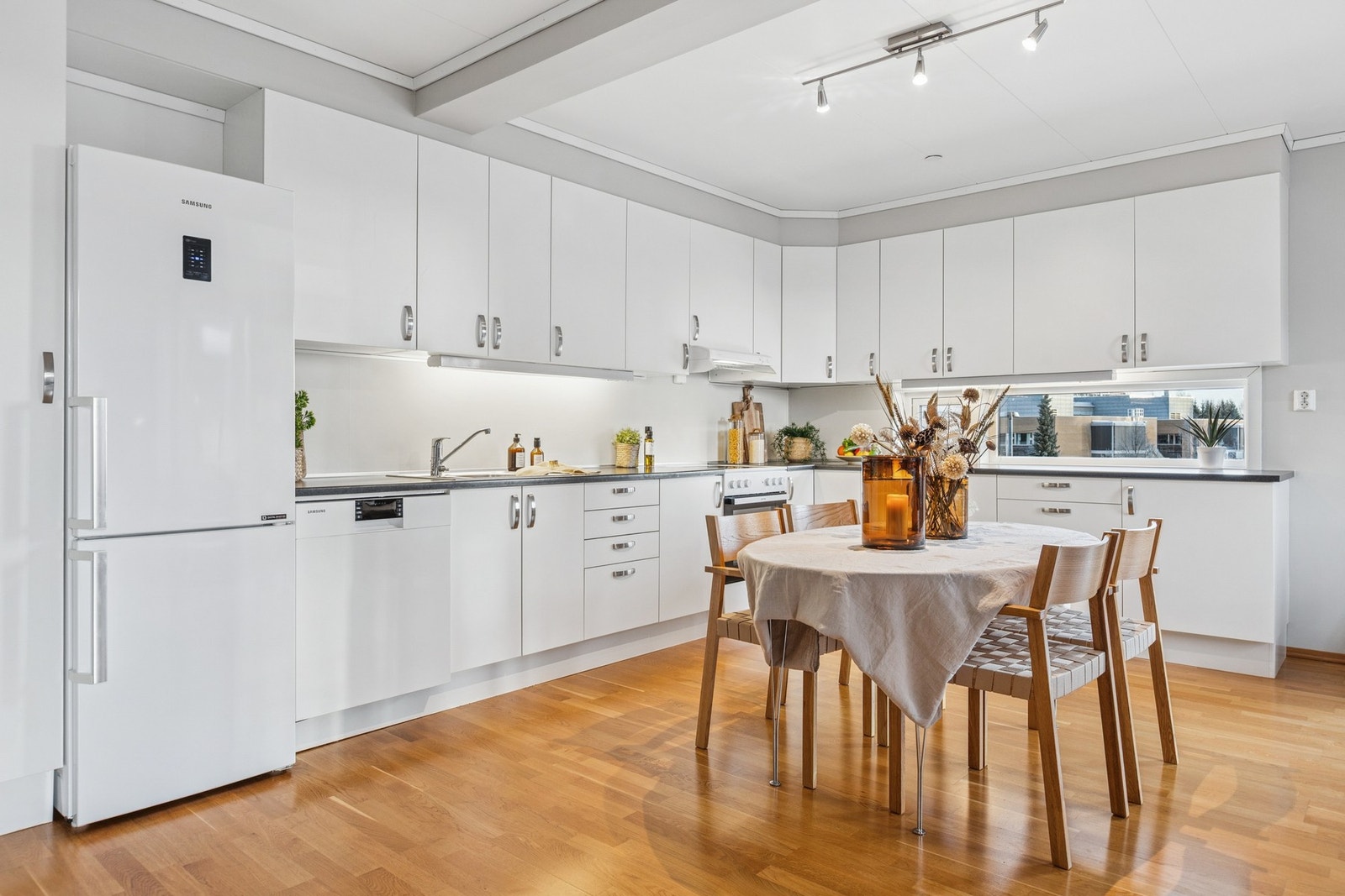 Kjøkkeninnredning med slette fronter fra byggeår. Benkeplater av laminat. Nedfelt oppvaskkum med ett-greps armatur. Automatisk vannstoppventil. Plater mellom kjøkkenbenk og overskap. Galleribilde