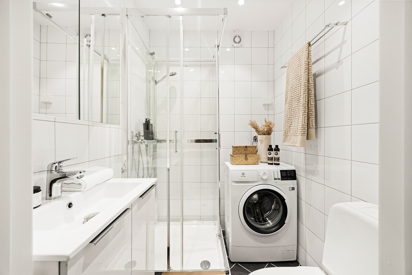 Videre er badet innredet med dusjkabinett med skyvedører (2024) og dusjbatteri med hånddusj. Galleribilde