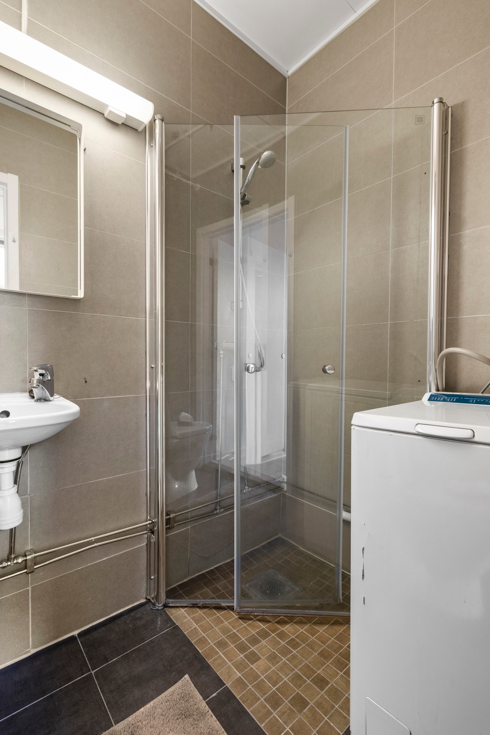 Dusjhjørnet har innadslående glassdører som utnytter plassen godt og gir en åpen følelse. I tillegg finner du servant med speil, toalett og opplegg for vaskemaskin. Galleribilde