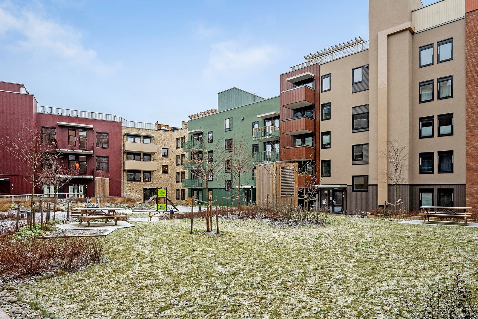 Lekeområder for barn i gårdsrommet som kombinerer grønt og lek. Det er brukt underlag av naturlige materialer som sand. Lekeområdene er avgrenset for trafikk. Galleribilde