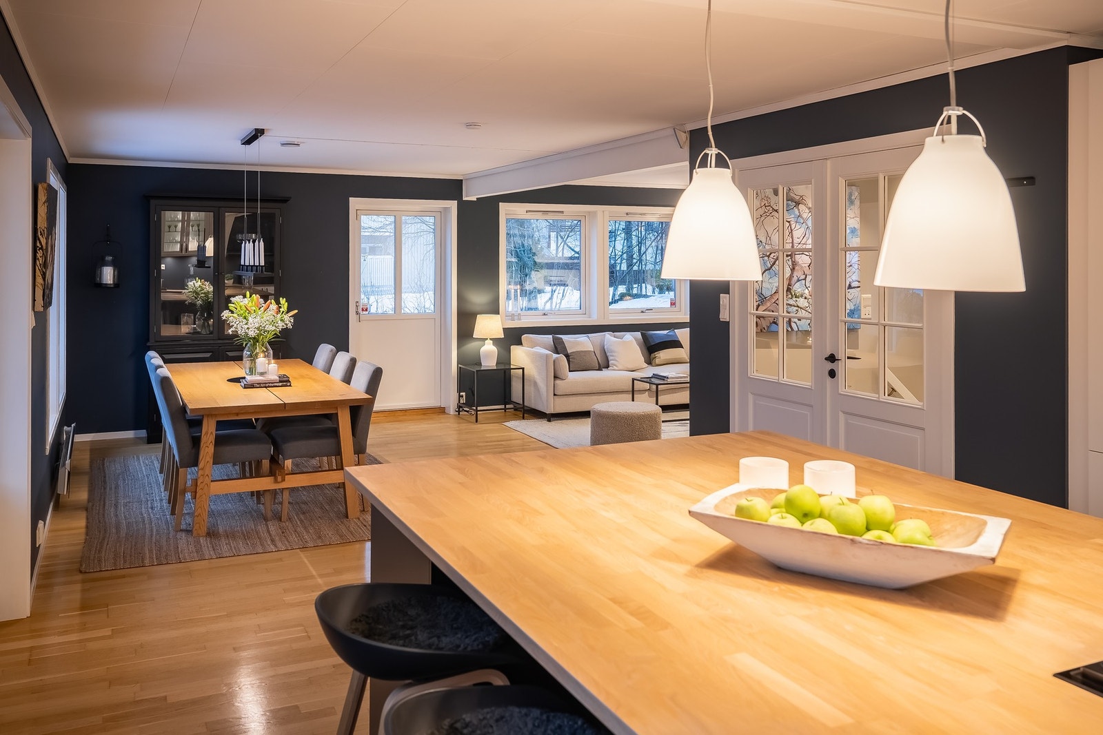 Stor kjøkkenøy med eikebenkeplate, stikkontakter og kjøkkenskap under. Galleribilde