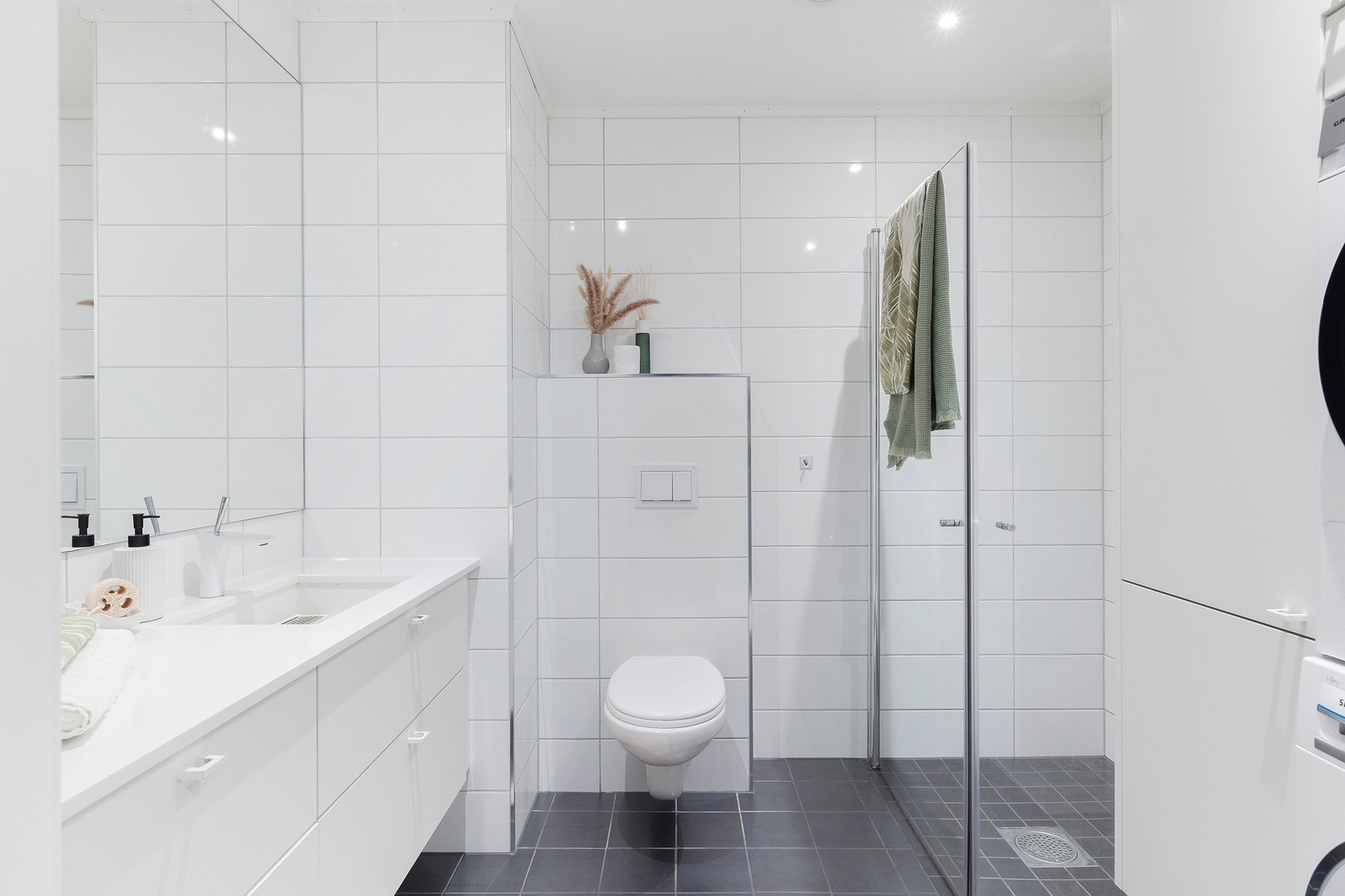 Baderommet har moderne innredning og opplegg for vaskemaskin Galleribilde