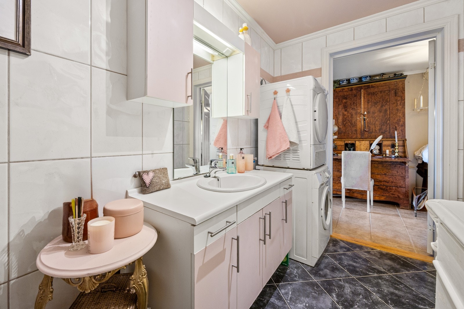 Badet er fra 1988 og har flislagte gulv- og veggflater. Det er innredet med servantmøblement med underskap og veggskap, samt gulvstående toalett. Galleribilde