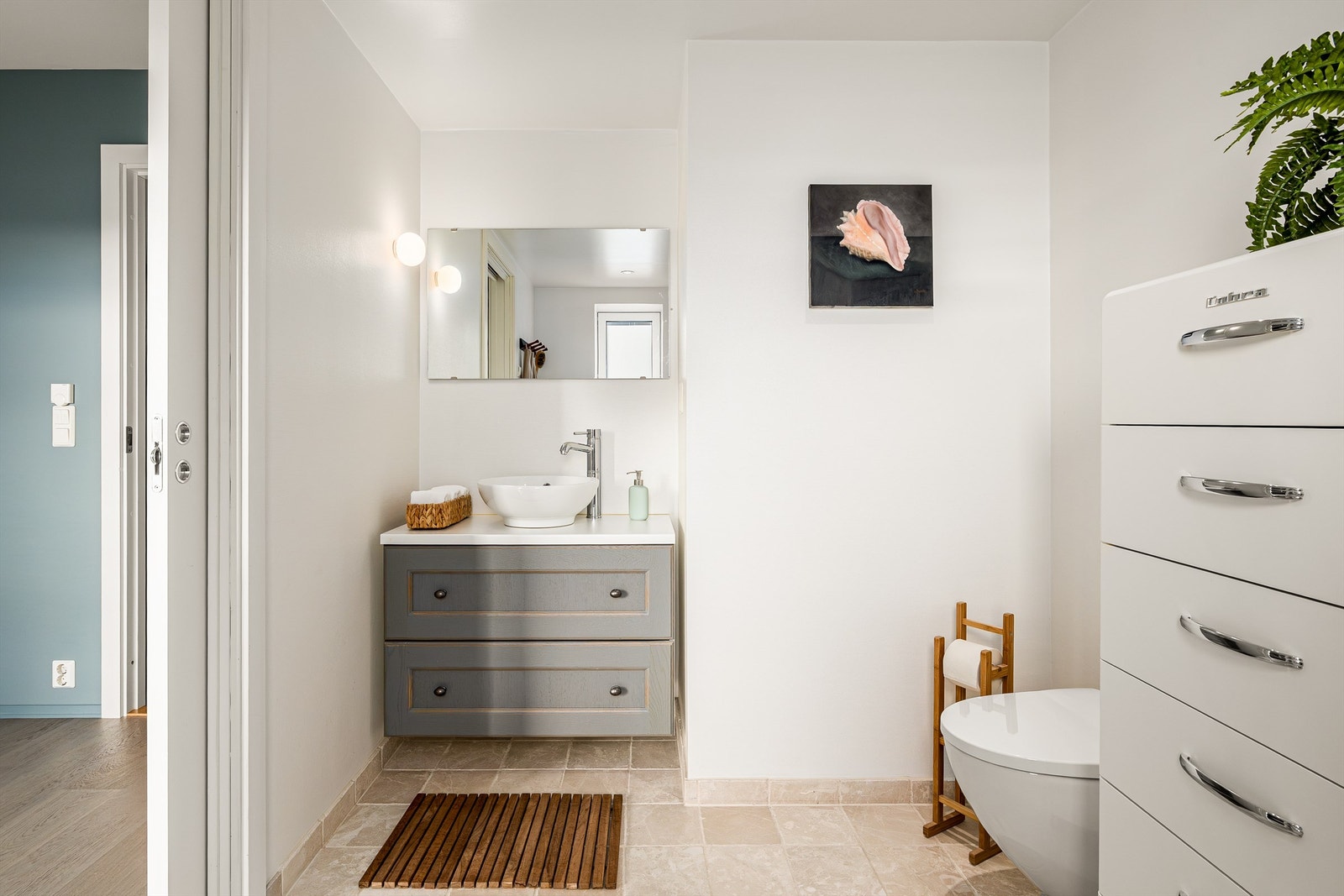 Badet er pent flislagt på gulv, med malte overflater på veggene. Det er gulvvarme, og himlingen har malt, slett flate med downlights. Galleribilde