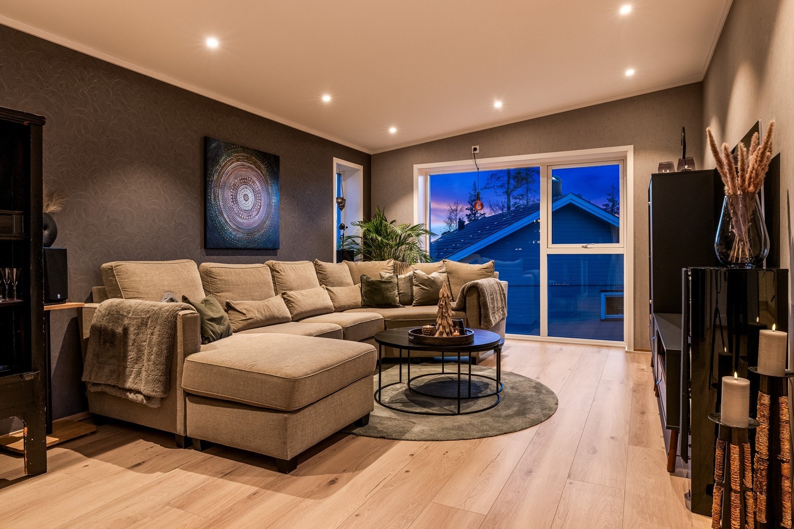 Stue med store vindusflater gir utsyn mot nærområdet og slipper naturlig lys inn i stuen. Galleribilde