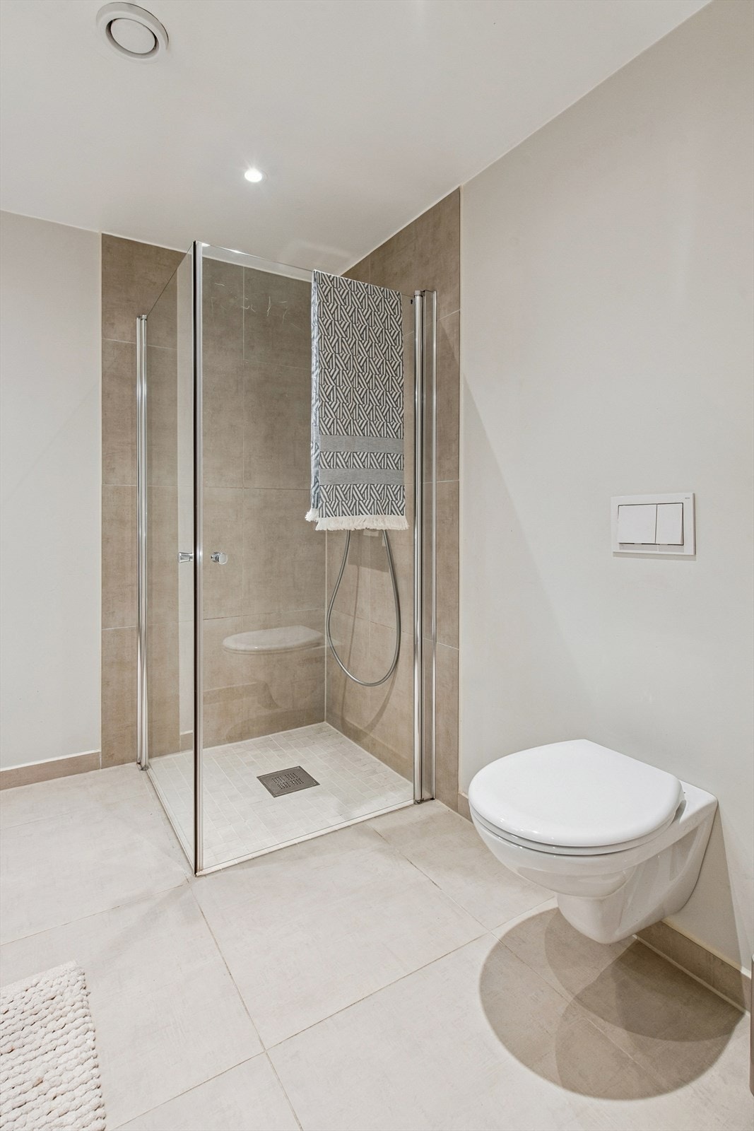 Dusjhjørne med innfellbare glassdører og vegghengt toalett for enkelt renhold. Galleribilde