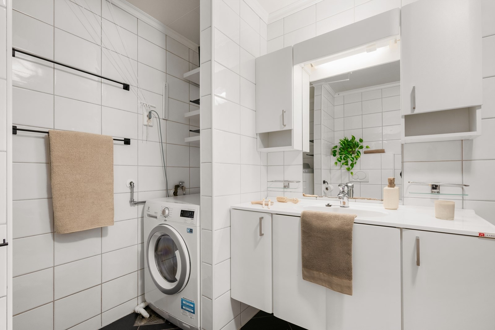 Helfliset bad med varmekabler i gulv. Badet har et stilrent og tidsriktig uttrykk, og er innredet med dusjvegger i glass og dusjgarnityr på vegg, vegghengt toalett samt innredning med servant. Vaskemaskin kan medfølge dersom dette er ønskelig Galleribilde