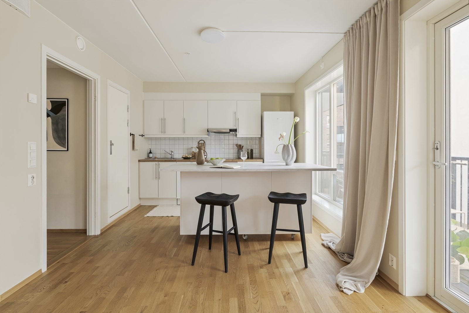 En romslig kjøkkenøy danner et naturlig bindeledd mellom kjøkken og stue, og skaper en sosial sone som egner seg like godt til hverdagsmåltider som til servering og samvær med gjester. Galleribilde