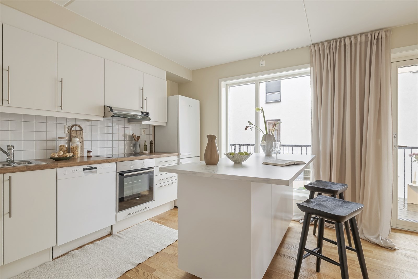 Kjøkkenet fremstår moderne og tidløst, med glatte fabrikklakkerte skapfronter og flislagt bakvegg som både er praktisk og lettstelt. Galleribilde