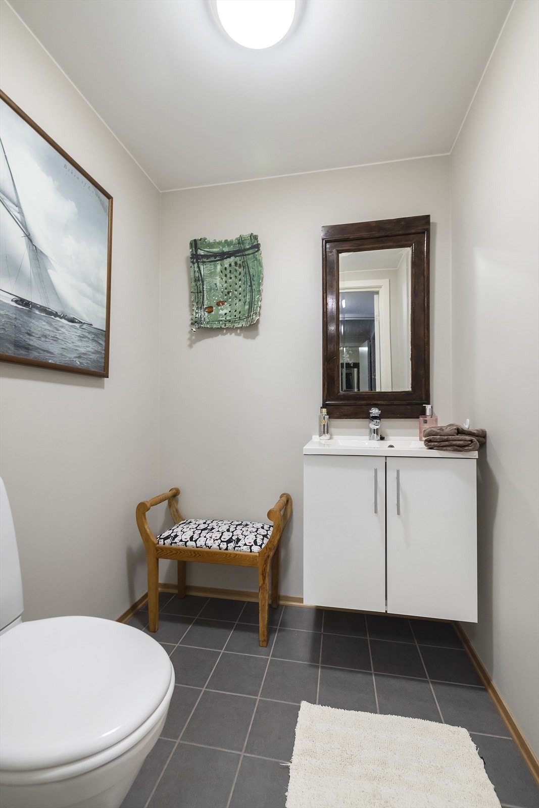 Toalettrom har flislagt gulv og malte vegger. Det er gulvmontert toalett og servantskap Galleribilde