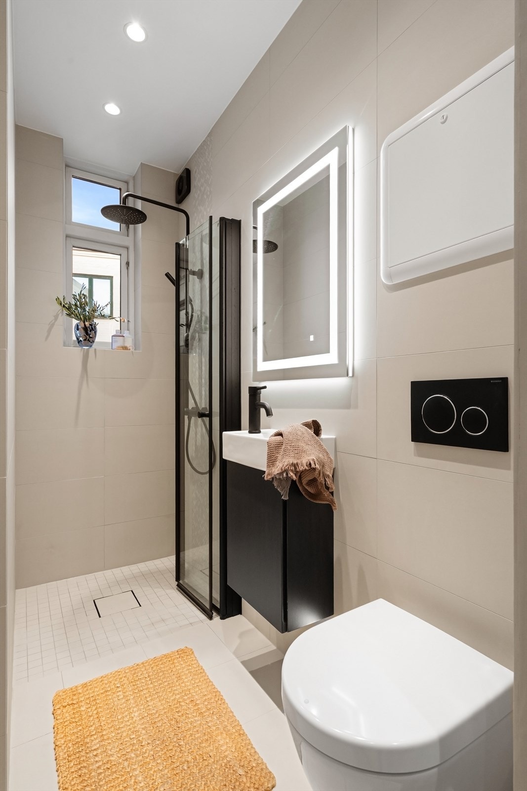 Badet er pusset opp i 2021, og har baderomsinnredning med glatte fronter, servant med speil og belysning, dusj med innfellbare glassdører samt veggfestet WC Galleribilde