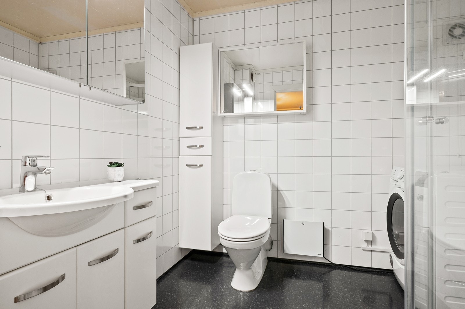 Lyst og funksjonelt baderom med våtromsplater på vegger og vinylbelegg på gulvet. Galleribilde