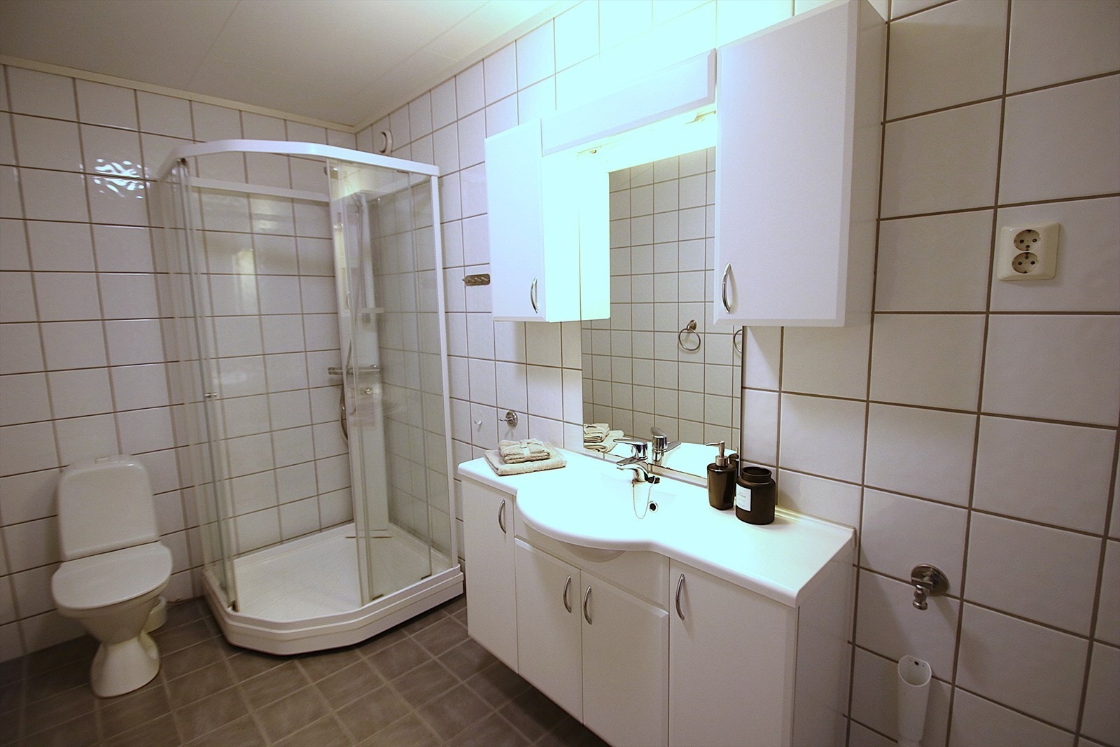 Baderommet er innredet med dusjkabinett, gulvmontert toalett, servant med skapinnredning. Galleribilde