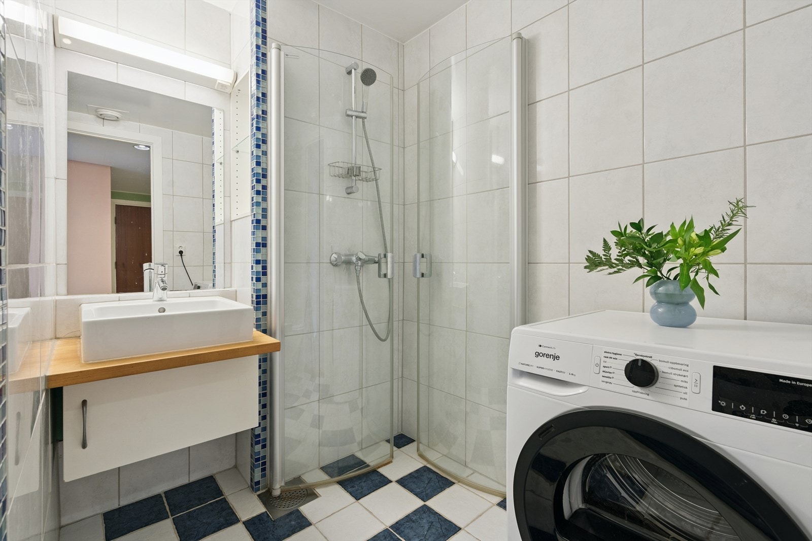 Badet er romslig, med fliser på vegger og gulv. Badet inneholder toalett, vask med innredning og dusj med vendbare dører. På badet finnet vi også tørketrommel Galleribilde