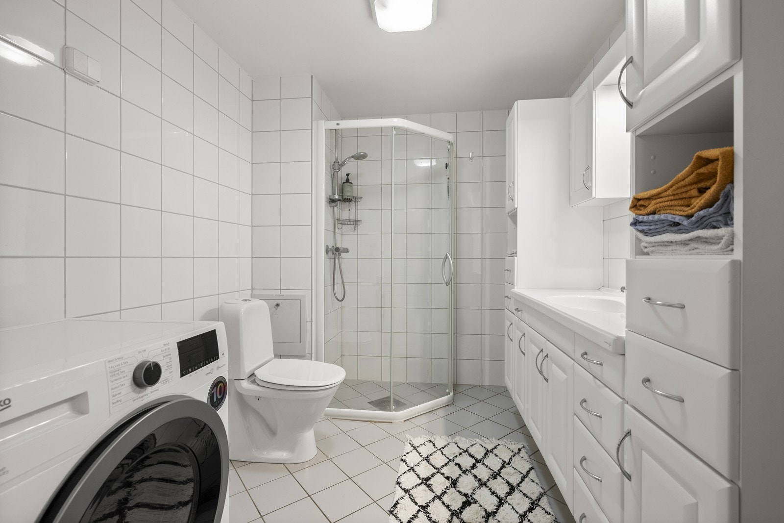 Badet er fra byggeåret og har flislagte overflater, dusjhjørne og opplegg for vaskemaskin. Galleribilde