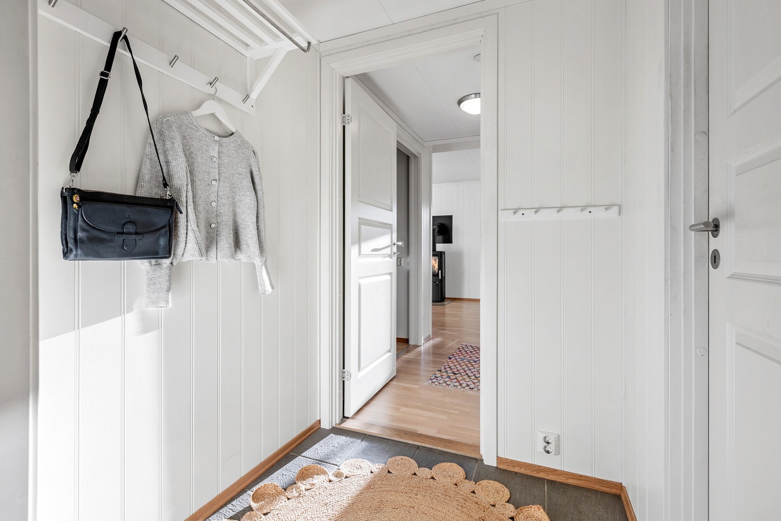 Gangen har lyse veggoverflater kombinert med flislagt gulv som gir en praktisk og stilren velkomstsone. Galleribilde