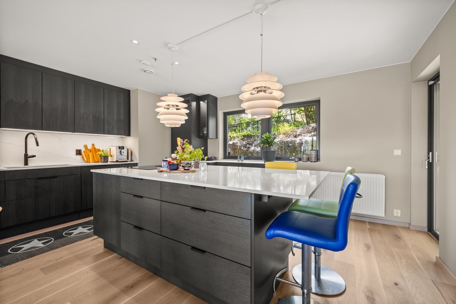 Praktisk utforming med innredning langs to vegger, kombinert med kjøkkenøy. Galleribilde