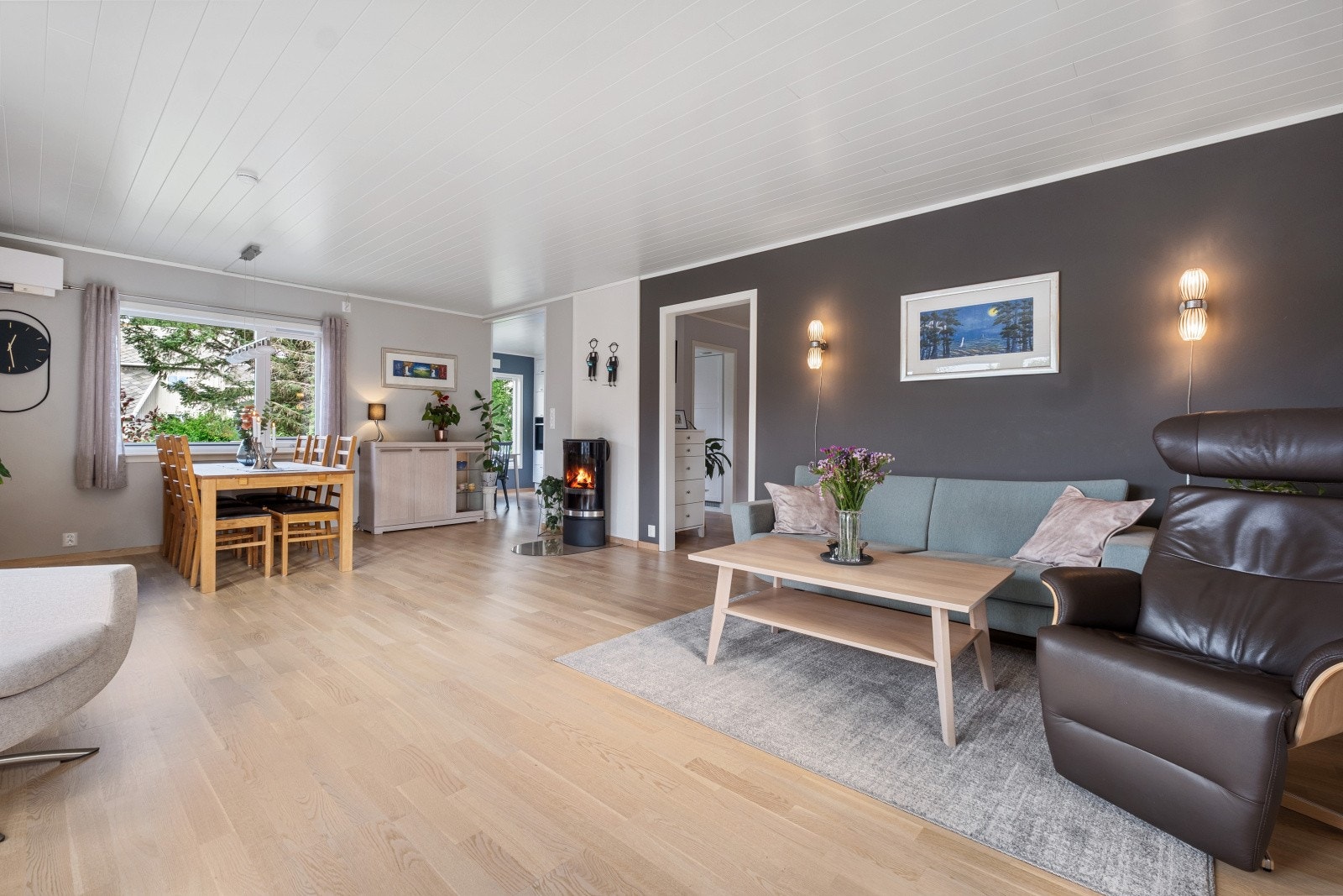 Stuen er utført med et lyst gulv, lysmalte overflater og en mørkere kontrastvegg som bryter opp mot det lyse Galleribilde