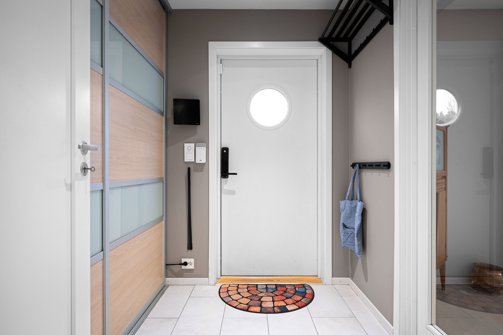 Innbydende flislagt entré med plass til å henge fra seg yttertøy i skyvedørsgarderobe. Galleribilde