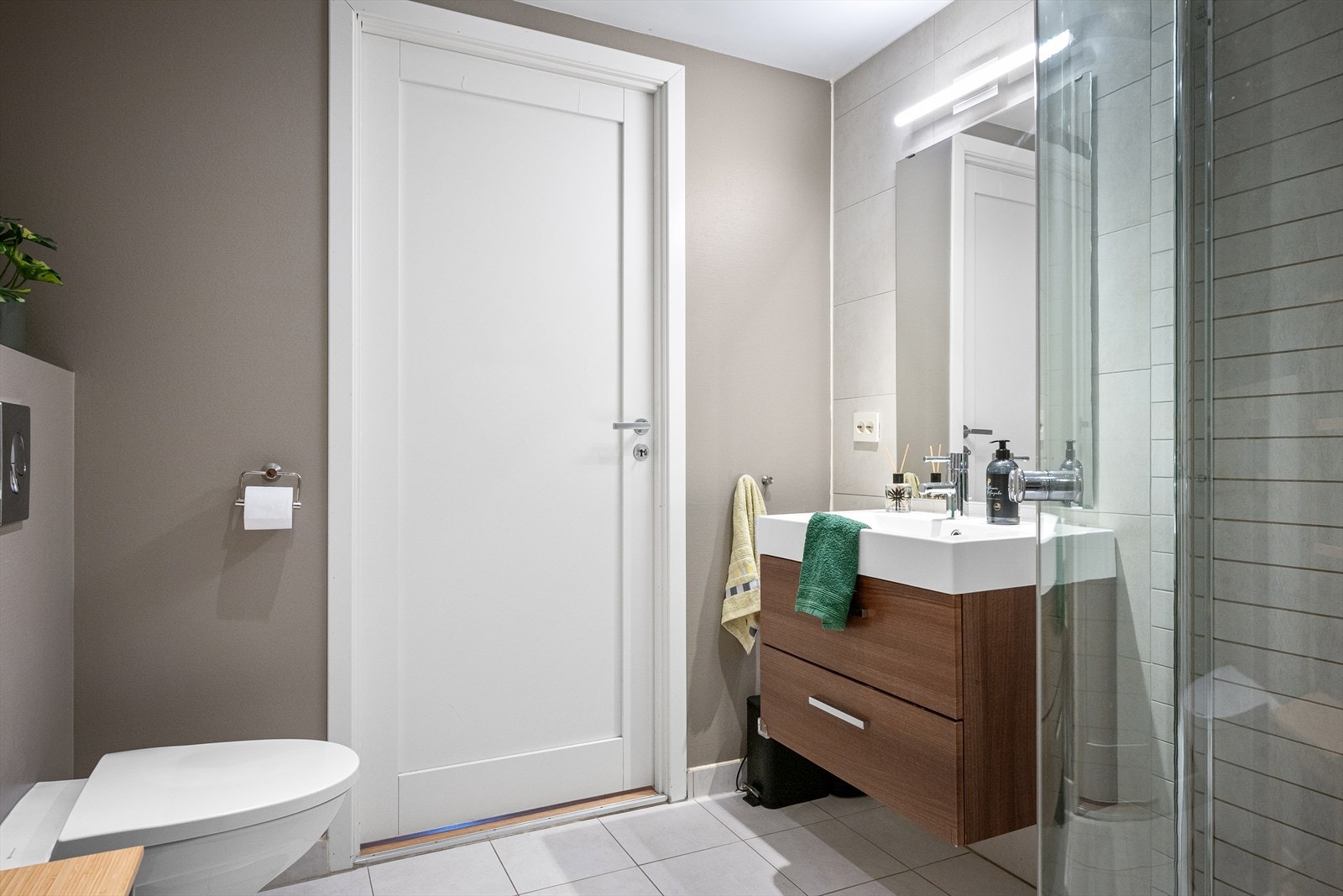 Badet er utstyrt med servant, vegghengttoalett og dusjhjørne. Galleribilde