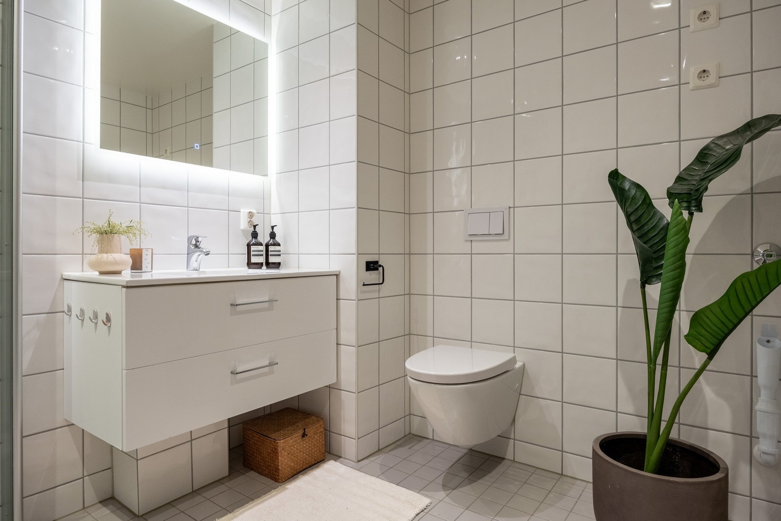 Det er vegghengt skap med ovenpåliggende servant, speil på vegg med LED-lys og vegghengt toalett. Galleribilde