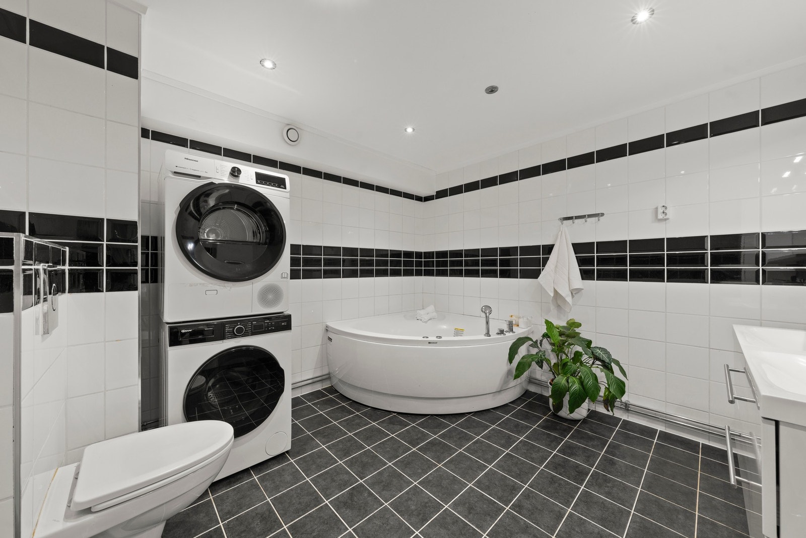 Romslig og delikat helfliset bad med et tidløst uttrykk, gjennomført fargevalg og god plass. Badet er innredet med boblebad, servant med innredning og vegghengt toalett, og byr på en funksjonell løsning som kombinerer komfort og praktisk bruk i hverdagen. Galleribilde