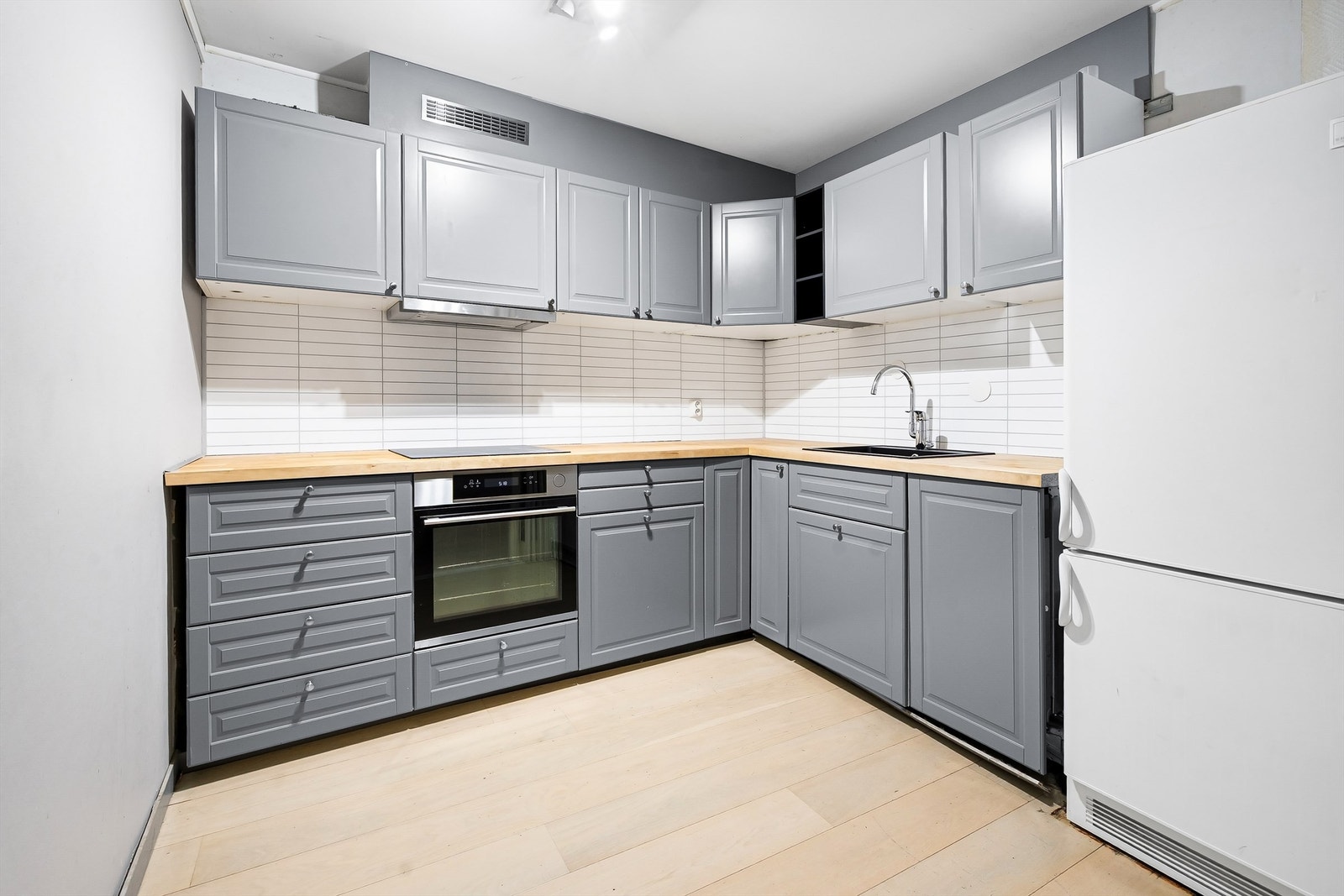 Delvis åpen kjøkkenløsning mot stue med profilerte fronter. Galleribilde