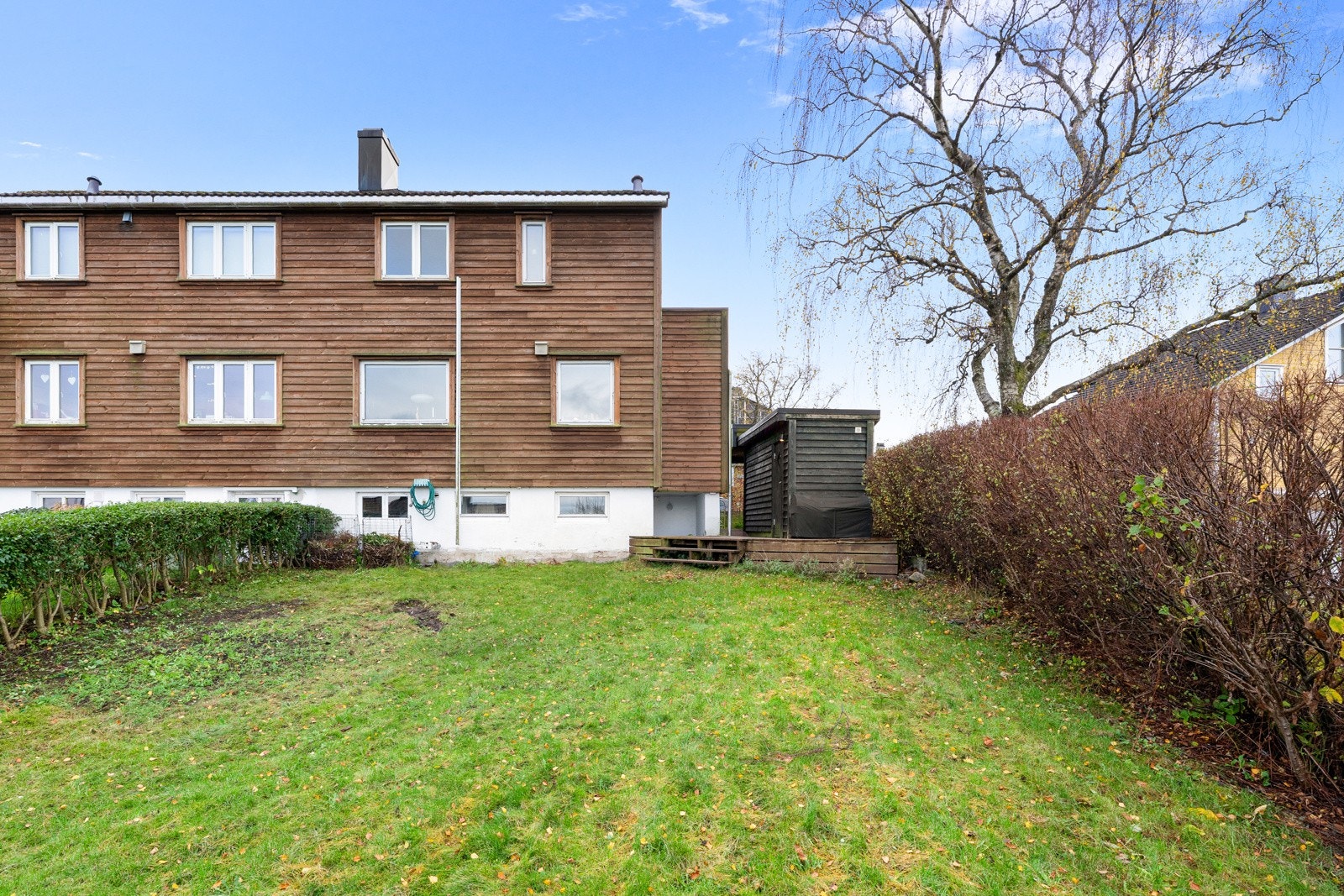 På baksiden av boligen åpner tomten seg ytterligere, og her ligger et stort grøntareal som gir rikelig plass til familieliv og lek. Galleribilde