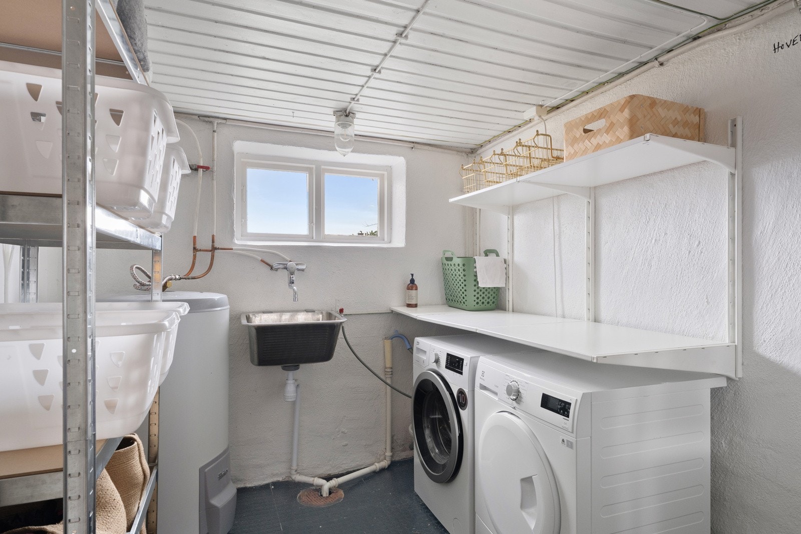 Vaskerommet ligger praktisk plassert i direkte tilknytning til kjellerstuen. Rommet har god arbeidsflate, utslagsvask, plass til vaskemaskin og tørketrommel samt gode oppbevaringsmuligheter som gjør det enkelt å holde orden på tøy og tekstiler. Galleribilde