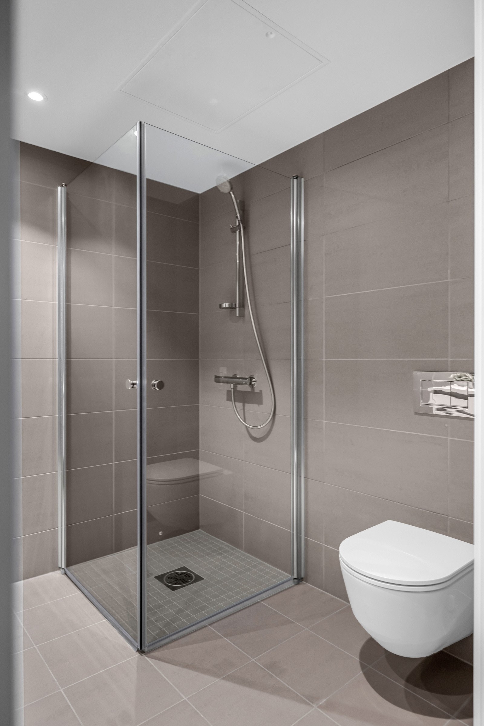 Badet er utstyrt med dusjnisje med glassdører, vegghengt toalett og servant med innredning. Galleribilde