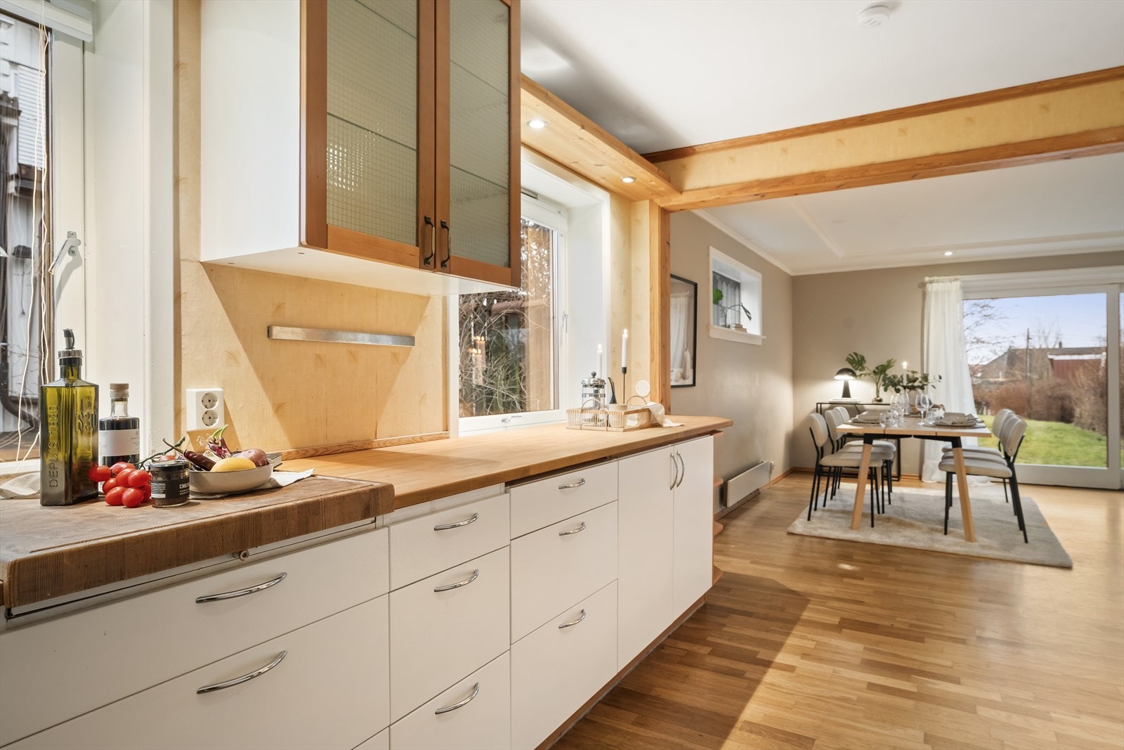 Punktvis spotbelysning, store vinduer og åpen løsning mot stue, noe som gir et sosialt og hyggelig oppholdsrom. Galleribilde