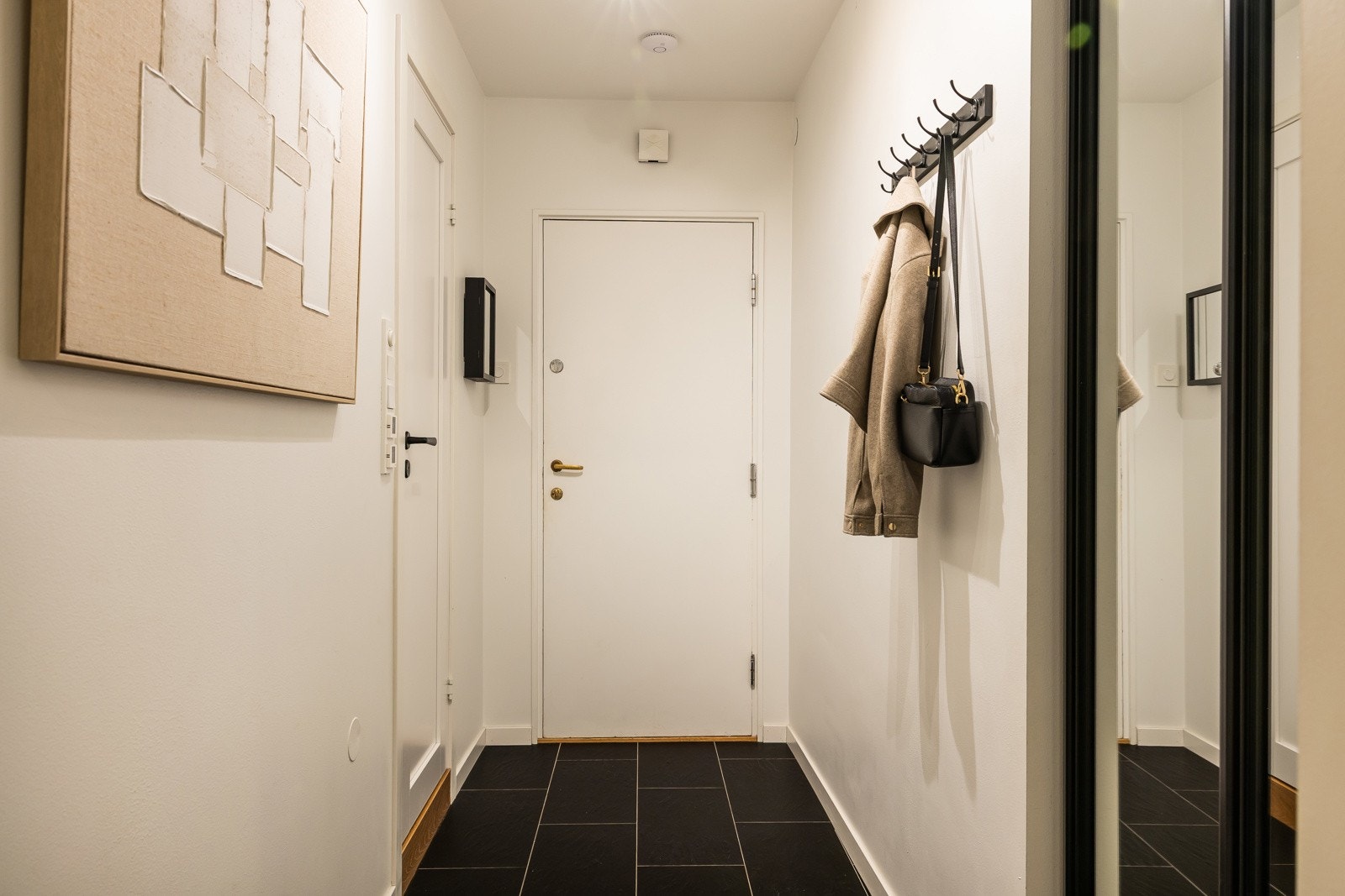 Entréen har flislagte gulv med varmekabler og garderobe med skyvedører. Galleribilde