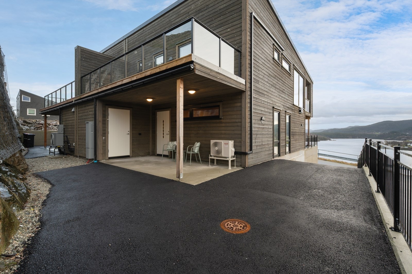 Asfaltert innkjørsel og biloppstillingsplass ved inngangspartiet. Galleribilde