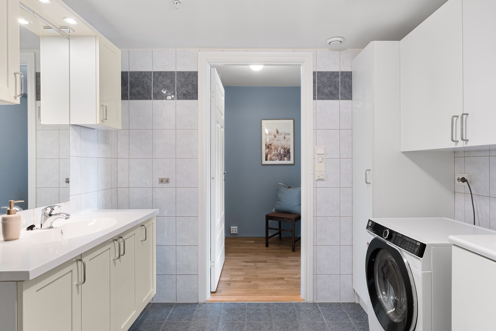 Bad er innredet med baderomsinnredning med nedfelt vask, høyskap, toalett, dusjhjørne og opplegg for vaskemaskin. Galleribilde