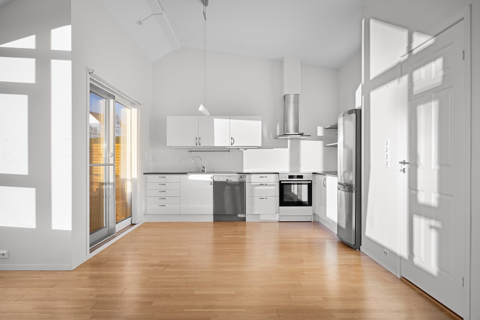 Stuen og kjøkken er i åpen løsning med god takhøyde og med store vinduer som slipper inn mye naturlig dagslys. Lyse, slette vegger og parkett. Galleribilde