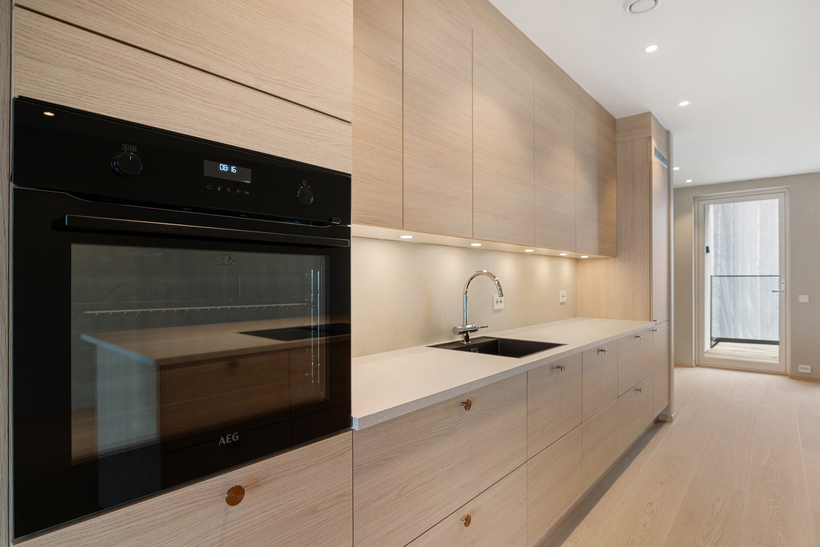 Fin belysning med spotter i tak og over benkeplaten. Her er det integrerte hvitevarer og god skapplass i skuffer og skap. Galleribilde