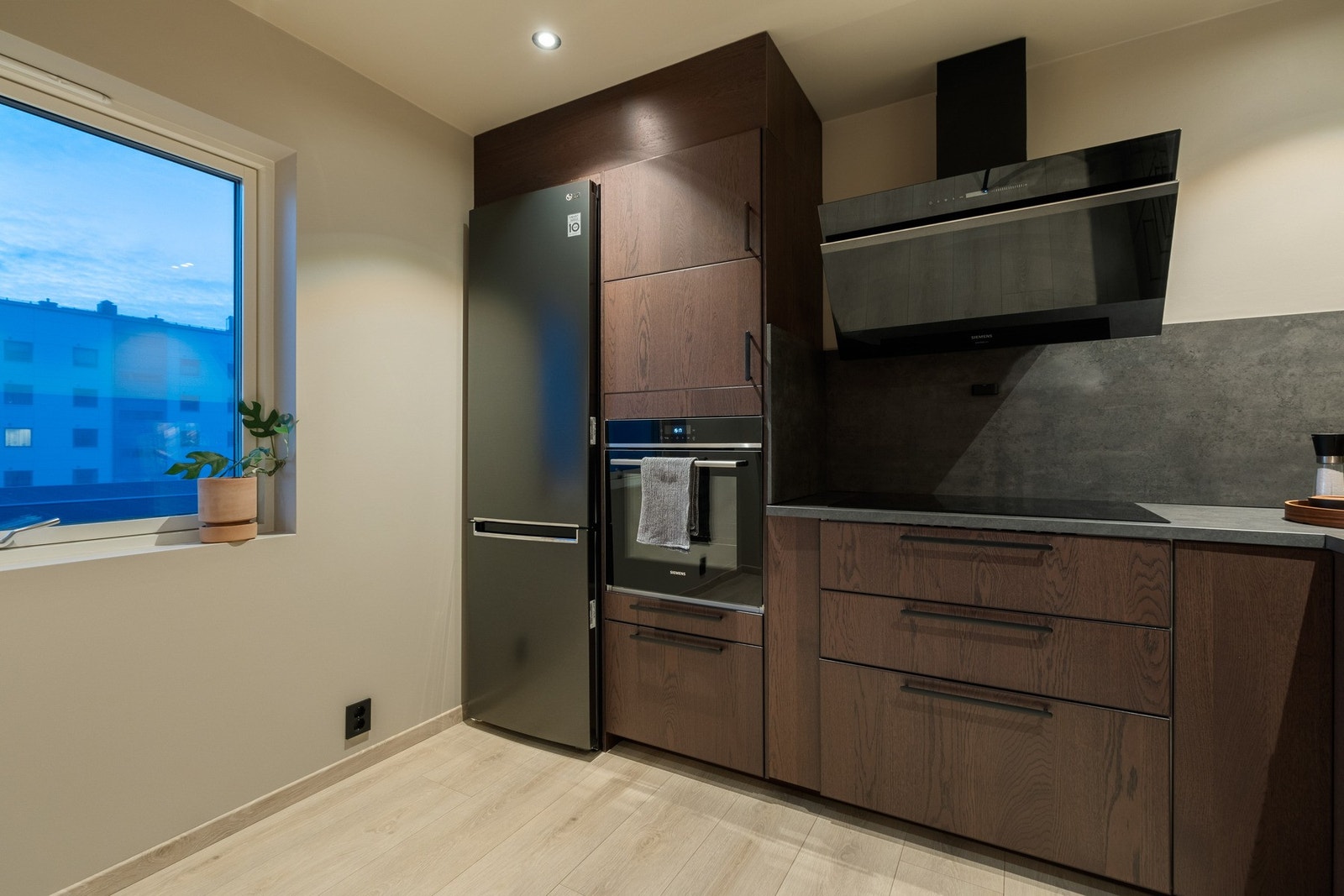 Kjøkkeninnredningen har plane fronter med integrert stekeovn og oppvaskmaskin, samt nisje for frittstående kjøle/fryseskap Galleribilde