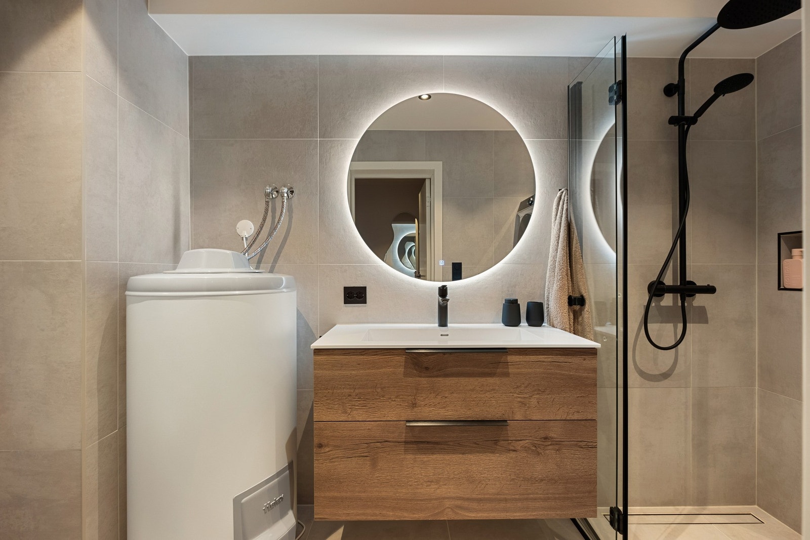 Bader er utstyrt med veggmontert servantinnredning og speil med integrert belysning. Dusjhjørne foldbart glassdører og veggintegrerte hylle. Badet er også utstyrt opplegg/avløp for vaskemaskin og varmtvannsbereder Galleribilde