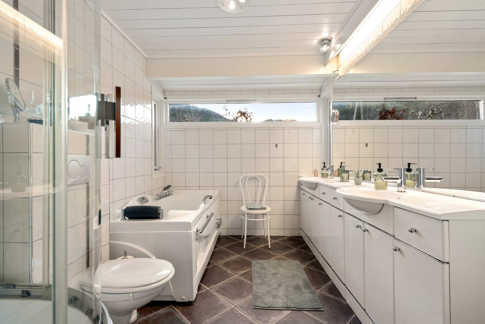 Romslig baderom oppusset i 2014. Stor og innholdsrik baderomsinnredning. Speil med overlys over servanter. Badet har forøvrig boblebadekar, steamdusjkabinett og vegghengt toalett. Galleribilde