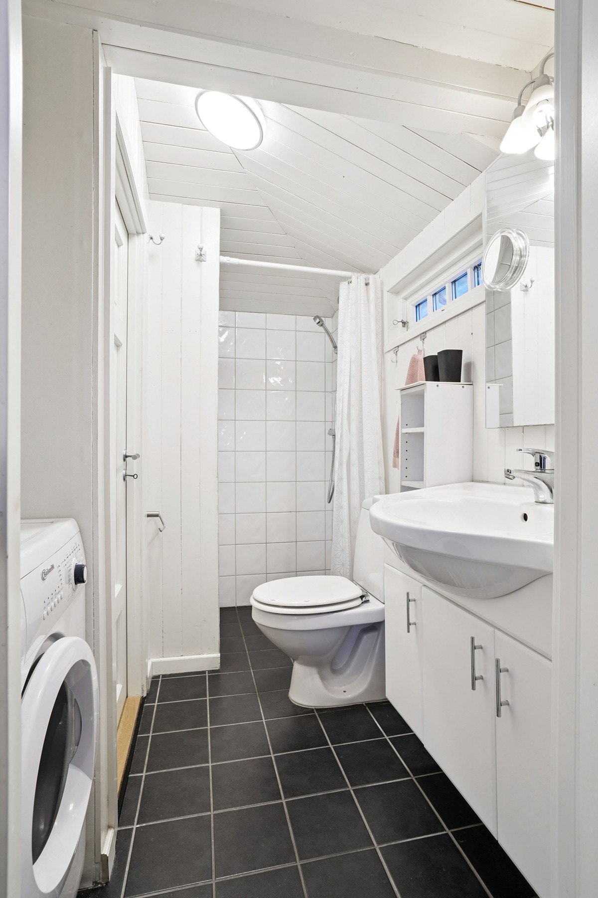 Badet har flislagt gulv med gulvvarme. Veggene har malt panel og i dusjsonen er det fliser. Galleribilde