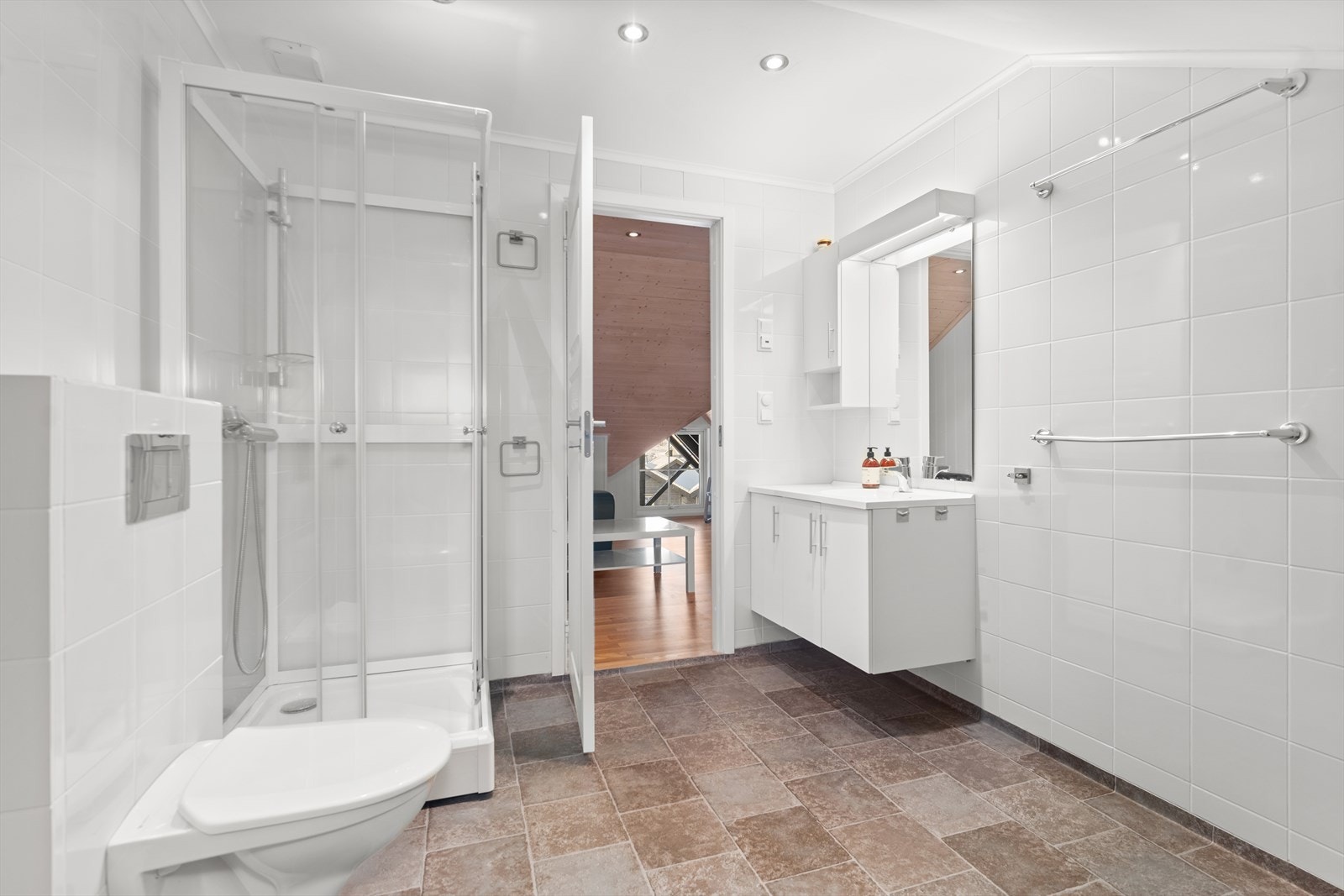 Romslig bad i loftsetasjen. Dusjkabinett, vegghengt klosett og baderomsinnredning. Galleribilde