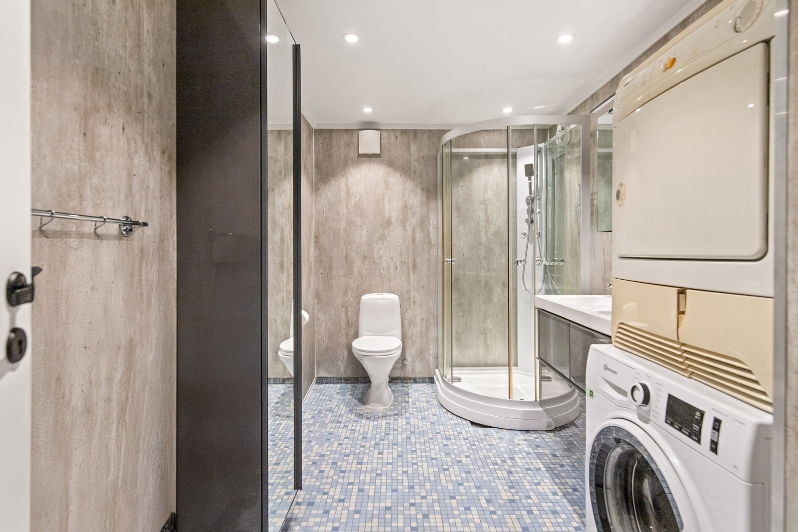 Baderomsinnredning av dobbel servant, skuffer og overskap med speil og overlys. Videre er det sokkeltoalett og dusjkabinett. Det er opplegg for vaskemaskin strømuttak til tørketrommel og ventilasjon via naturlig avtrekk. Galleribilde