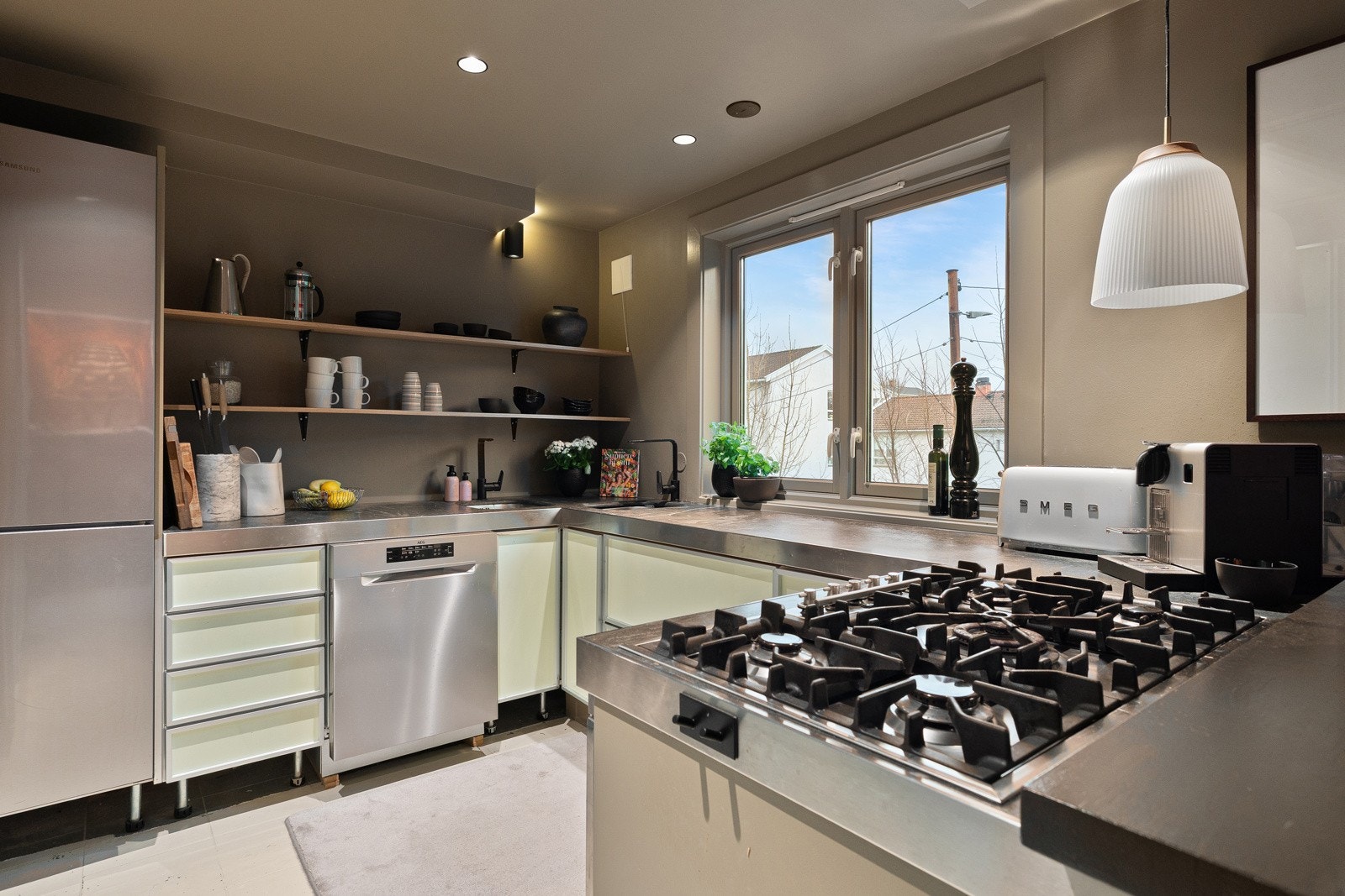 Åpne hyller og moderne detaljer gir et luftig uttrykk, mens gasskoketoppen og de integrerte hvitevarene gjør kjøkkenet funksjonelt i hverdagen. Galleribilde