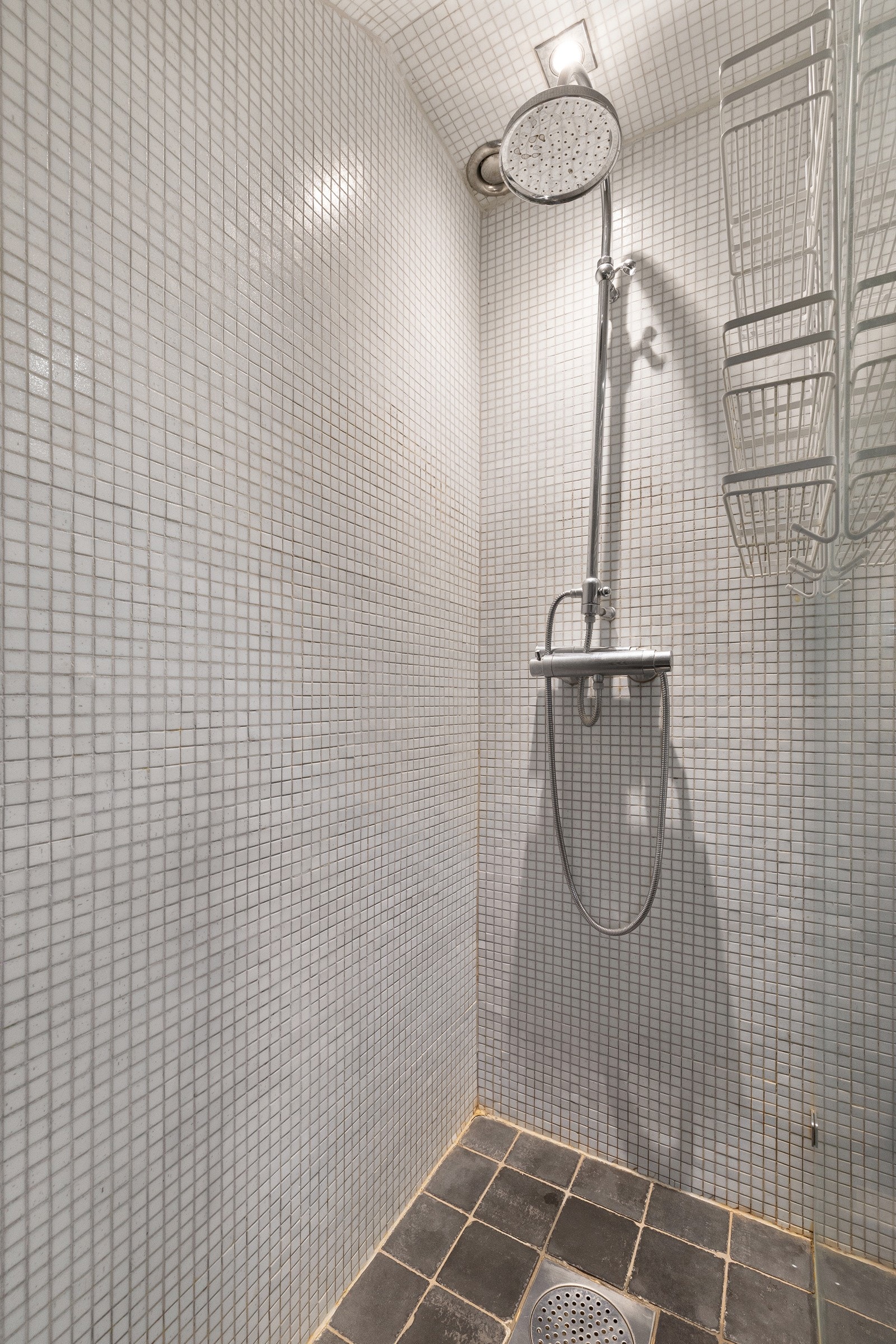 Overflatene består av fliser på gulv med elektriske varmekabler, samt mosaikkfliser på både vegger og i himling, noe som gir rommet et helhetlig og moderne uttrykk. Galleribilde