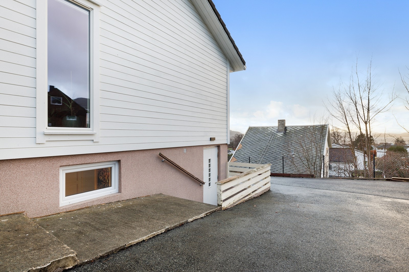 Kjellerinngang med enkel adkomst via asfaltert gangvei og hvitmalt ytterdør. Galleribilde