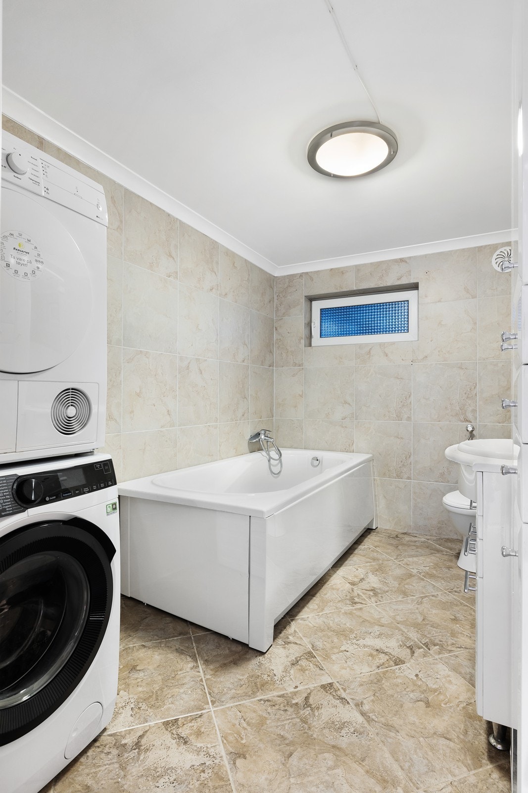 Flislagte vegger og gulv gir badet et helhetlig uttrykk, men teknisk rapport indikerer behov for totalrenovering (kilde: tilstandsrapport). Galleribilde