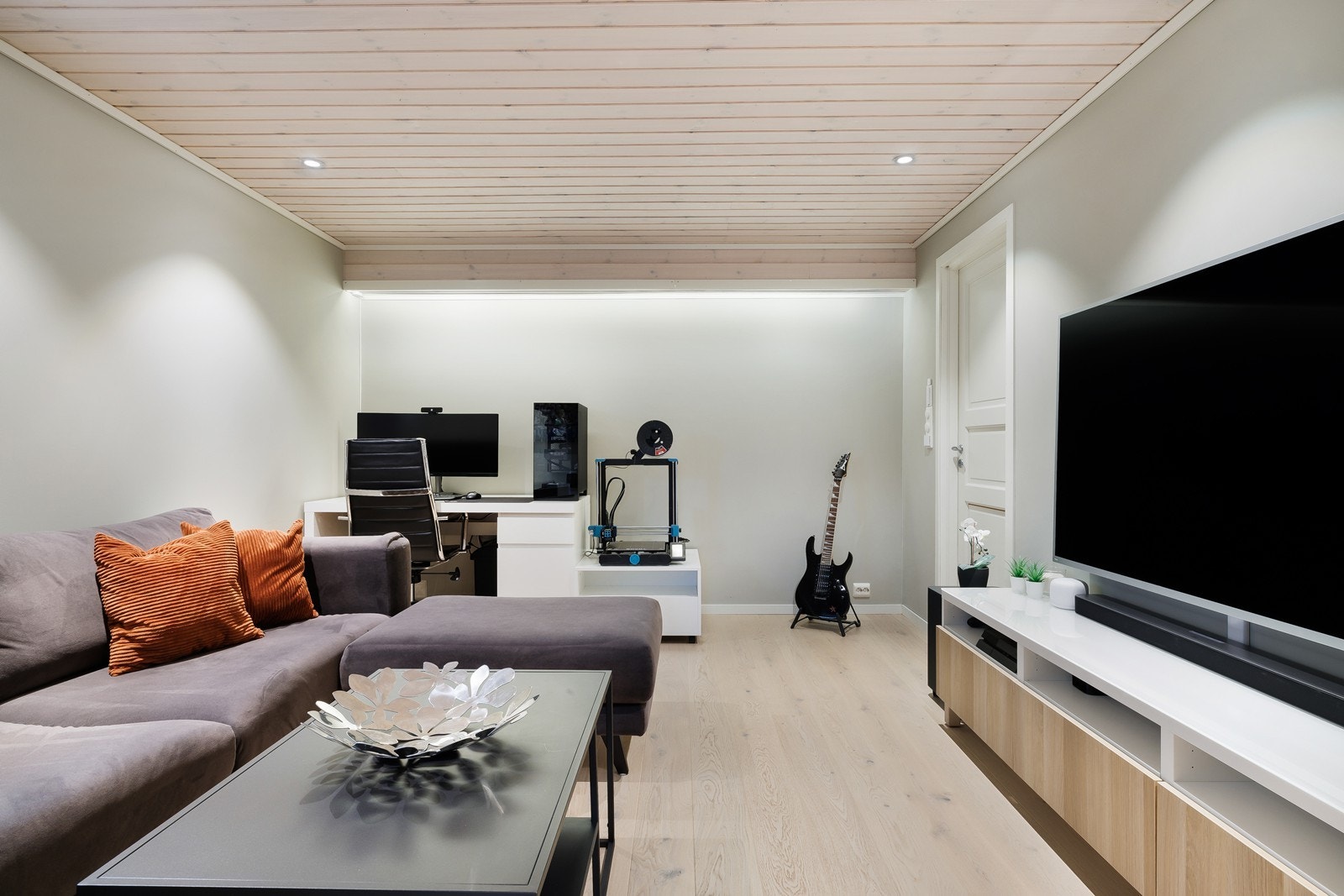 Plass til både underholdning og arbeidshjørne i kjellerstuen, med praktisk innredning og vindu som gir naturlig lys. Galleribilde